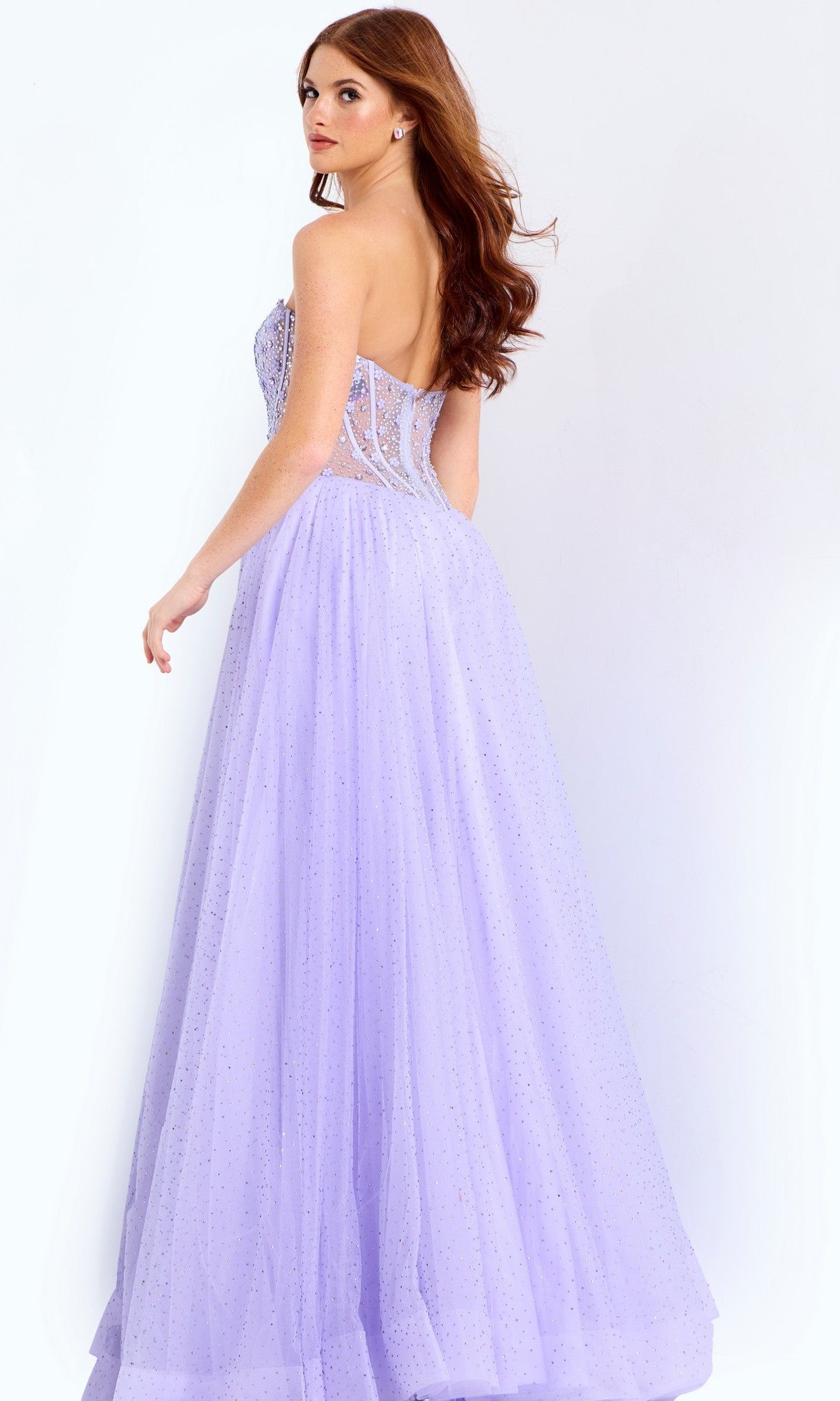 A woman models the Jovani 48309 long prom dress, featuring a strapless embellished corset bodice and tulle skirt, as she looks over her shoulder against a plain white background.
